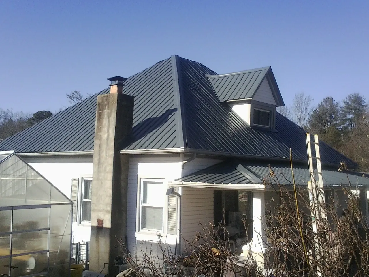 Dark blue standing seam metal roof on a white farmhouse with dormer — Slate & Tile Roof Repair by Roofing Brothers in Quinebaug