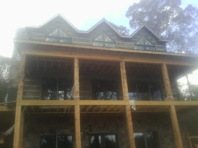 Dormers and porch framing on a large log home under construction — Roof Coating work by our crew in Quinebaug