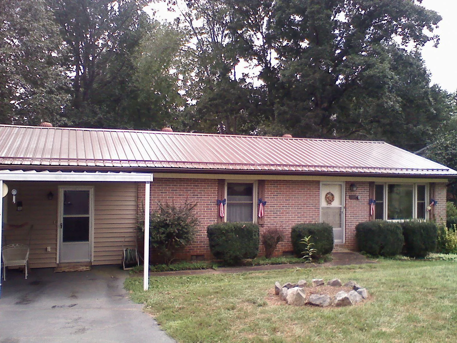 Bronze metal roof and carport on a brick ranch home — Roof Repair work by our crew in Quinebaug