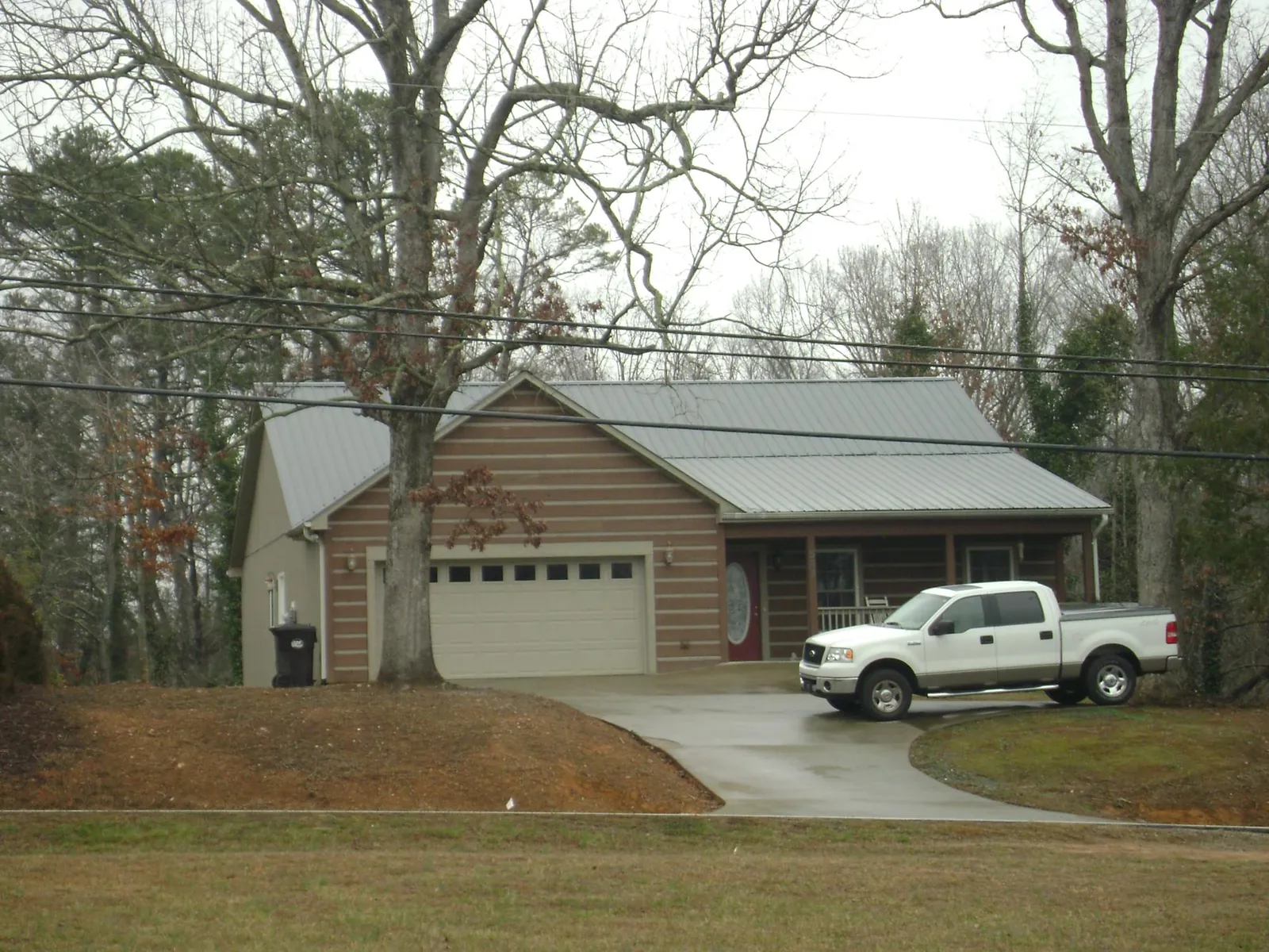 Gray metal roof on a log sided house with an attached two car garage in Quinebaug