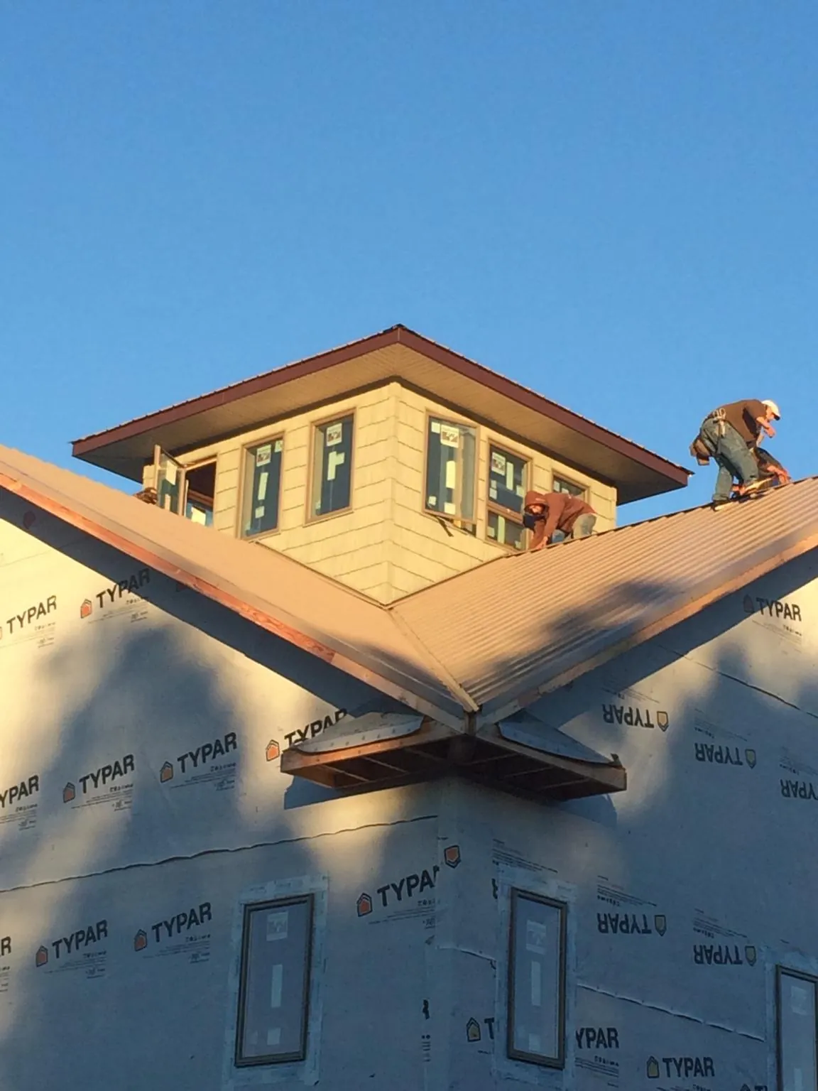 Roofers working around a rooftop cupola on a new metal roof at sunset — Roof Waterproofing in Quinebaug by Roofing Brothers